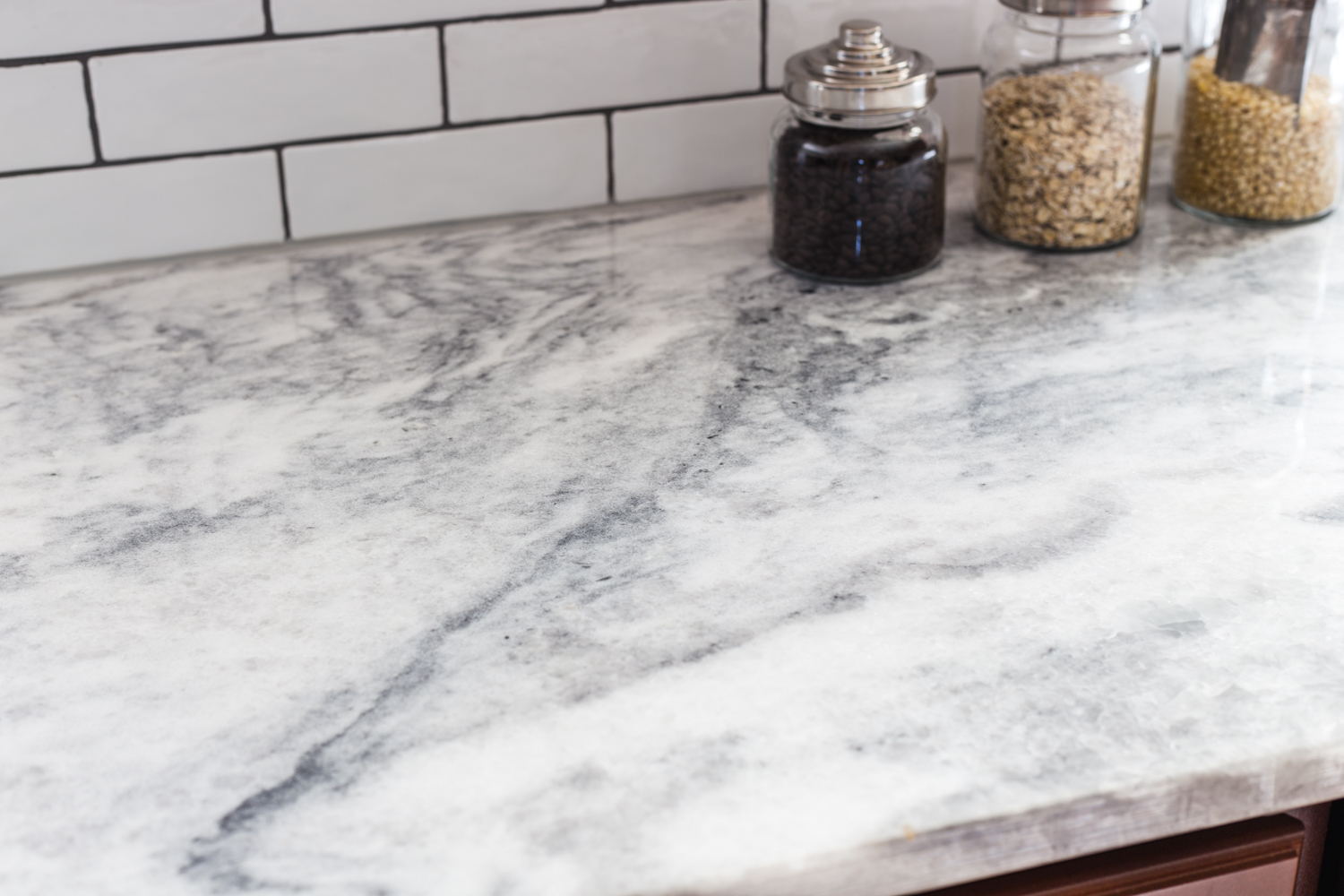 quartzite countertop with white subway tile and dark grout