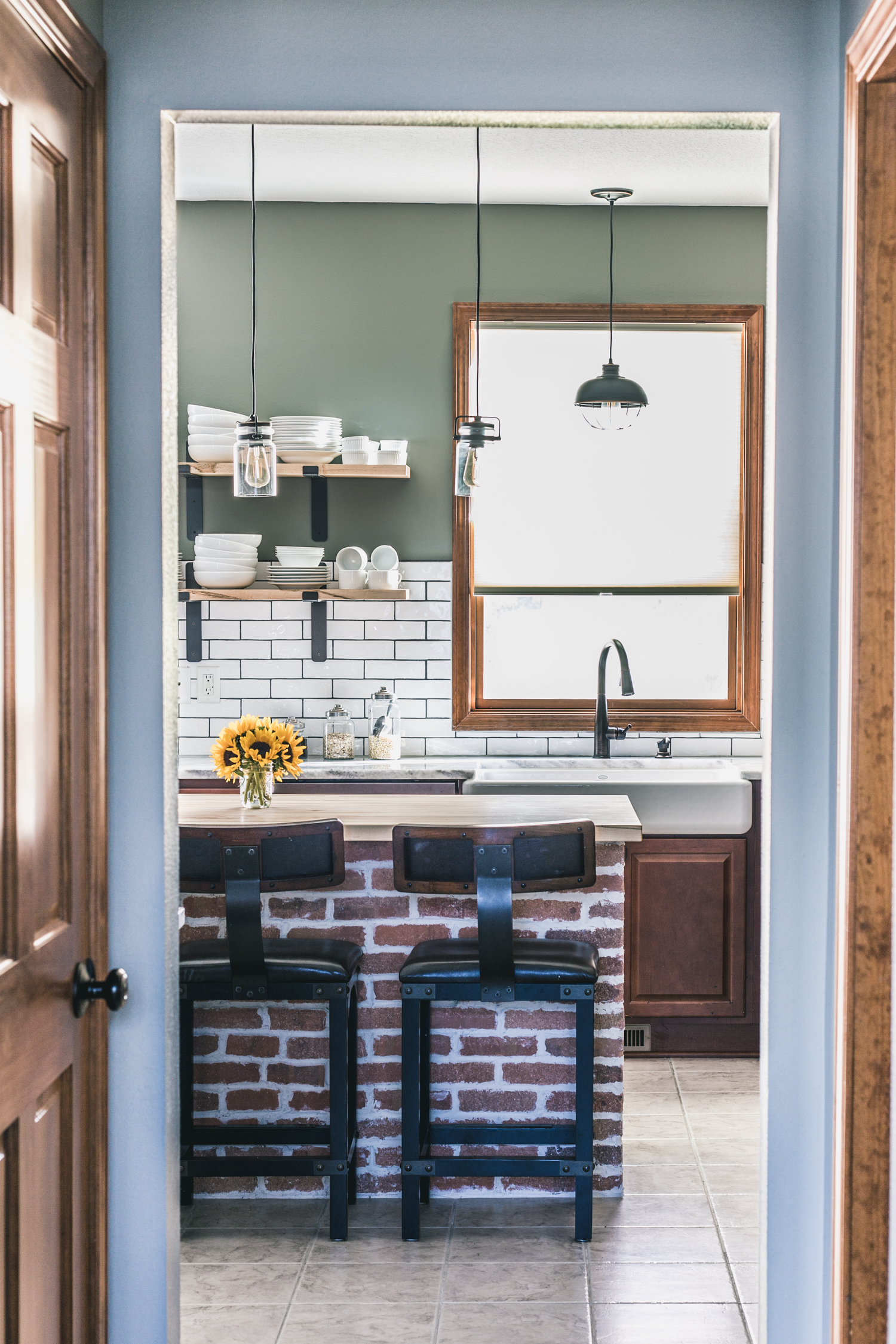 kitchen with exposed brick island, open shelving, and white subway tile
