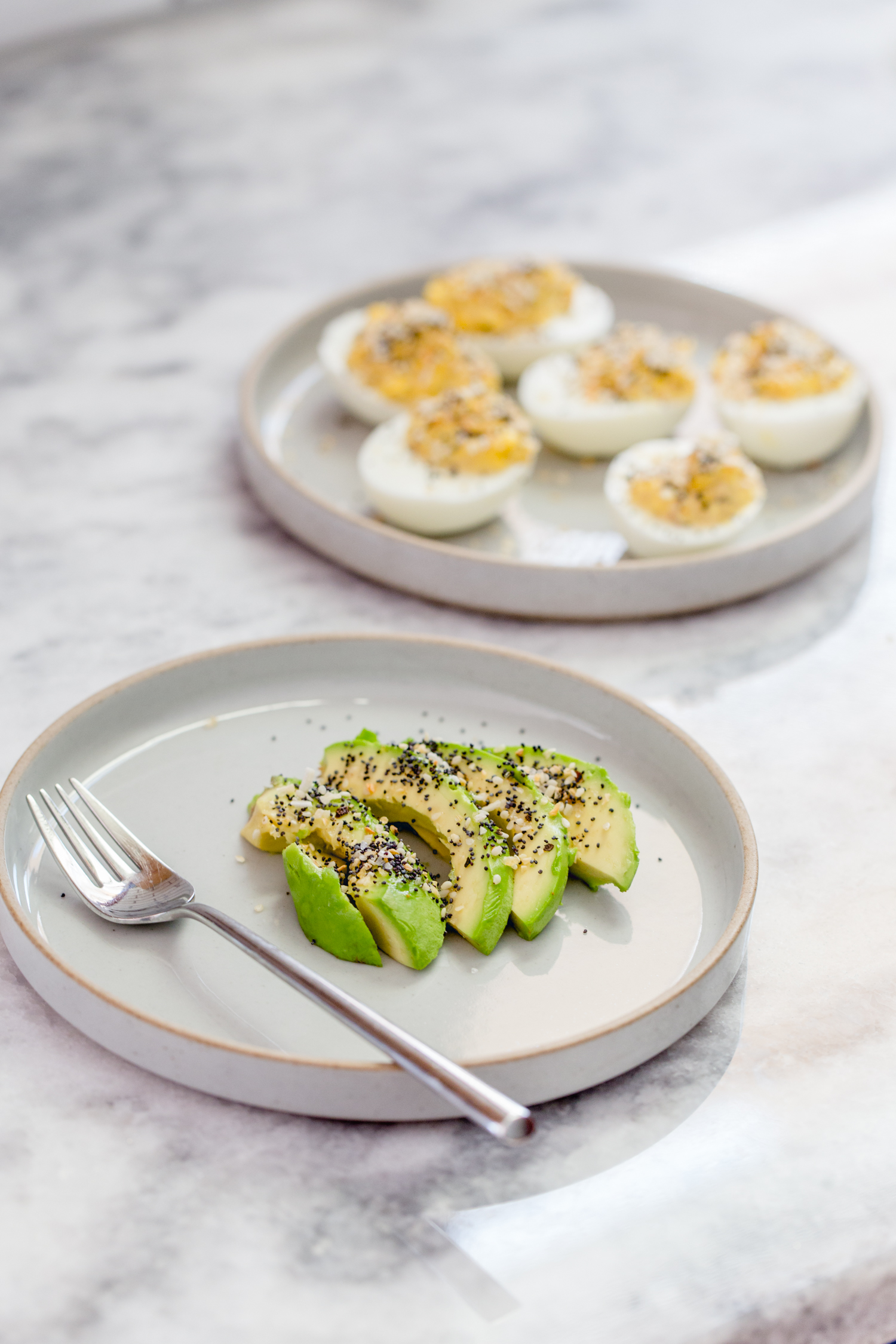 plate with sliced avocado and a plate with deviled eggs